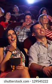 Young Couple Sitting In Cinema, Watching Movie, Eating Popcorn, Smiling.