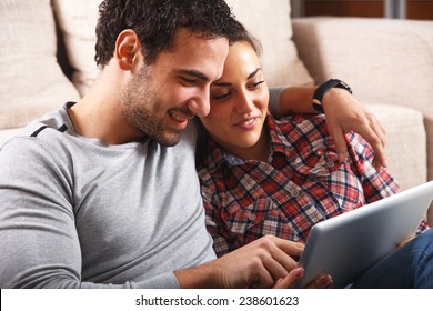 Young couple sitting  in the living room and using tablet.They shopping something online.