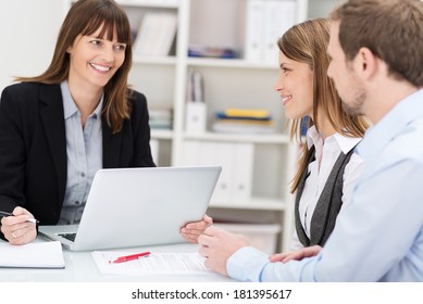Young couple sitting in an office talking to a woman broker or investment adviser