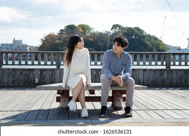 A young couple sitting on a bench and having a fun conversation - Powered by Shutterstock