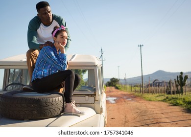 Young Couple Sitting On Car Bonnet At Countryside