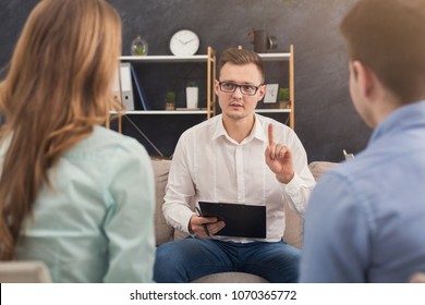 Young Couple Sitting On Couch During Therapy Session, Back View. Therapist Listening And Giving Advices To Married Man And Woman With Relationship Problems, Family Issues Concept, Copy Space