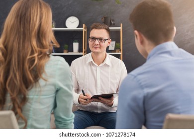 Young Couple Sitting On Couch During Therapy Session, Back View. Therapist Listening And Giving Advices To Married Man And Woman With Relationship Problems, Family Issues Concept, Copy Space