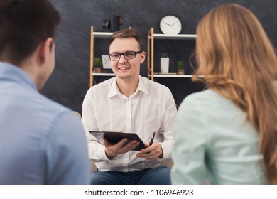 Young Couple Sitting On Couch During Therapy Session, Back View. Therapist Listening And Giving Advices To Married Man And Woman With Relationship Problems, Family Issues Concept, Copy Space