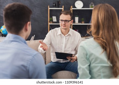 Young Couple Sitting On Couch During Therapy Session, Back View. Therapist Listening And Giving Advices To Married Man And Woman With Relationship Problems, Family Issues Concept, Copy Space