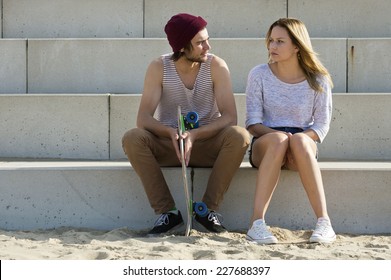 Young Couple Sitting On Large Concrete Steps, Engaged In A Deep, Personal Conversation