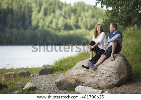 Young couple sitting on a rock by the river. Honeymoon.