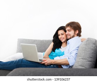 Young Couple Sitting On A Sofa Happy Smile, Using Laptop, Portrait Of Lovely Young Man And Woman Hug, Embrace On The Couch, With Cope Space