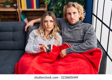 Young Couple Sitting On The Sofa At Home Thinking Attitude And Sober Expression Looking Self Confident 