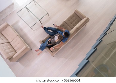 Young Couple Sitting On A Sofa In The Luxury Living Room, Using A Tablet Computer Top View