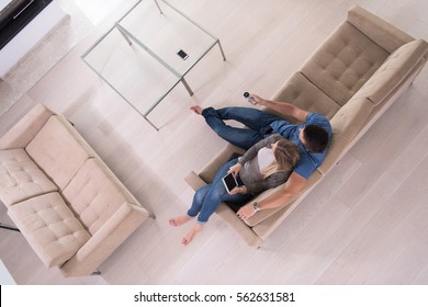 Young Couple Sitting On A Sofa In The Luxury Living Room, Using A Tablet Computer Top View