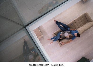 Young Couple Sitting On A Sofa In The Luxury Living Room, Using A Tablet Computer Top View