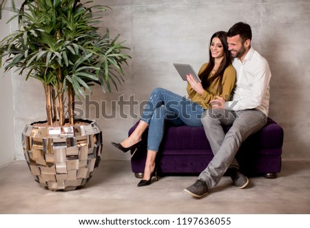 Young couple sitting on a sofa with a digitaltablet