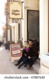 Young Couple Sitting Outside A Diner In A Small Town.