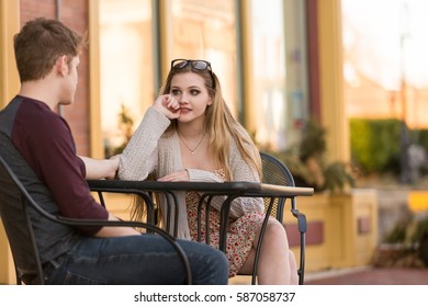 Young couple sitting at an outside table engaged in conversation.
