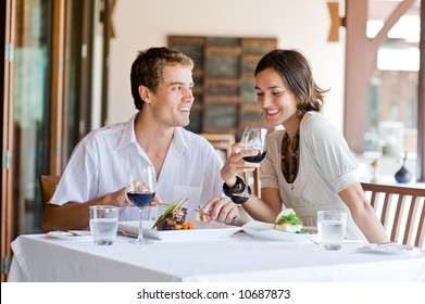 A young couple sitting at a table at an outdoor restaurant - Powered by Shutterstock