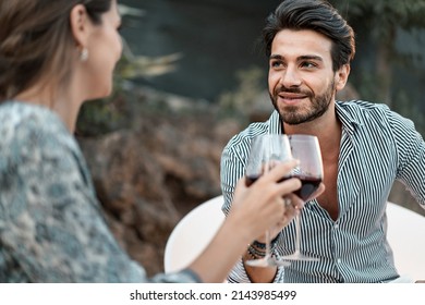 Young couple sitting at a terrace party talk carefree and spend time together drinking red wine - intimate moment of millennial generation bonding to each other - Powered by Shutterstock