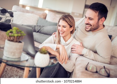 Young couple sitting in they living room and using laptop.