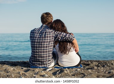 Young couple sitting together on beach 