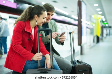 young couple sitting at underground platform awaiting train - Shutterstock ID 592226054
