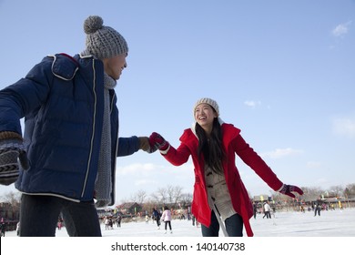 Young Couple Skating At Ice Rink