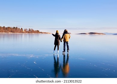 Una pareja joven está patinando en el helado lago Baikal. Hielo transparente. Viaje en invierno, recreación activa, deportes. 