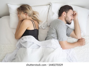 Young Couple Sleeping Back To Back In Their Bed