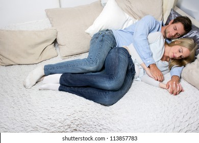 Young Couple Sleeping Next To Each Other On A Couch