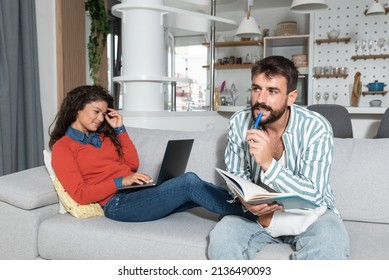 Young Couple Small Business Owners Working From Home. Married Man And Woman Sitting On Sofa In Apartment Work On New Commercial Ideas And Strategy For Web Site And Company They Own. Selective Focus.