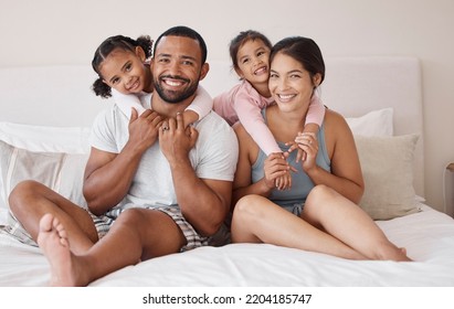 Young Couple Smile On Bed, With Children In Their Home Or Apartment. Happy Multicultural Family, In Bedroom With Toddler Kids While On Weekend Vacation Or Holiday Together For Portrait