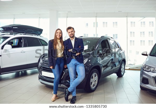 Young couple smiling at\
auto showroom