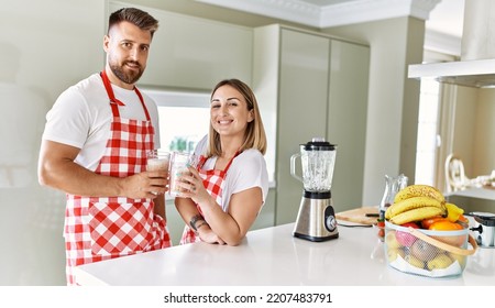 Young couple smiling confident holding glass of smoothie at kitchen - Powered by Shutterstock