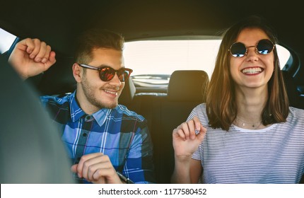 Young Couple Smiling And Dancing In The Back Seats Of A Car