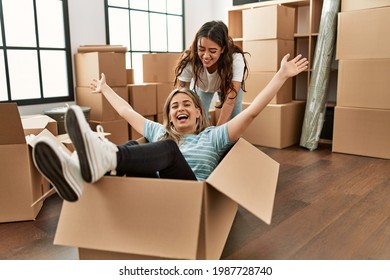 Young Couple Smiling Happy Playing Using Cardboard Box As A Car At New Home.