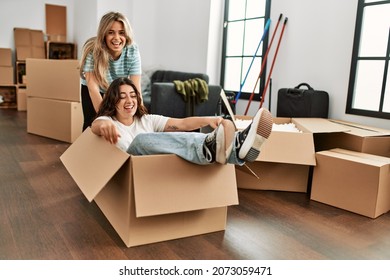 Young Couple Smiling Happy Playing Using Cardboard Box As A Car At New Home.