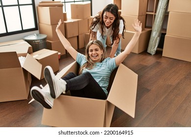 Young Couple Smiling Happy Playing Using Cardboard Box As A Car At New Home.