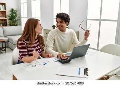 Young Couple Smiling Happy Using Laptop Sitting On The Table At Home.