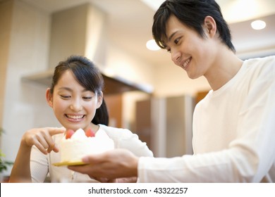 A young couple smiling and having cake