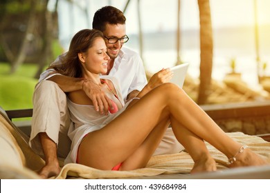 
Young couple smiling and looking at tablet pc, sitting on  luxury sunbed - Powered by Shutterstock