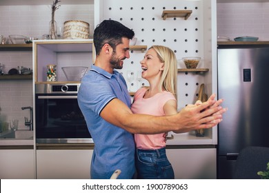 Young couple smiling while cooking healthy food in kitchen at home.