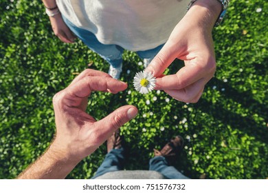 young couple in sneakers stands opposite on daisy Meadow and enjoying the love of nature, high angle footsie or flortrait, personal pespective from above.