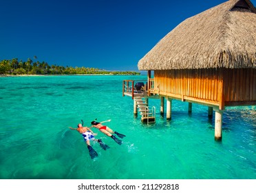 Young couple snorkeling from hut over blue tropical lagoon - Powered by Shutterstock