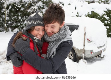 Young Couple In Snow With Car