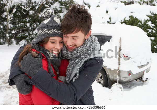 Young couple in snow with\
car