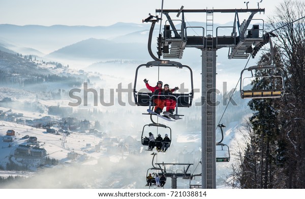 Young couple snowboarders riding up at ski lift\
at skiing and snowboarding winter resort in the mountains copyspace\
lifestyle vacation travelling sport extreme concept, Bukovel,\
Ukraine
