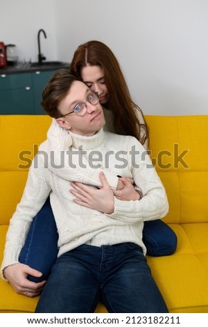 a young couple spend time at home together. Fooling around sitting on the couch. A man tries on a girl's hair