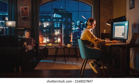 Young Couple Spending Time at Home, Working on Computers from Their Stylish Loft Apartment in the Evening. Female Resting on the Sofa and Browsing Social Media on Laptop. Man Designing UX Interface. - Shutterstock ID 2160027847