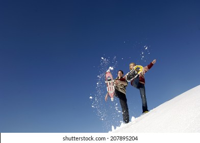 Young Couple Splashing Snow With Snow Shoes, Low Angle View