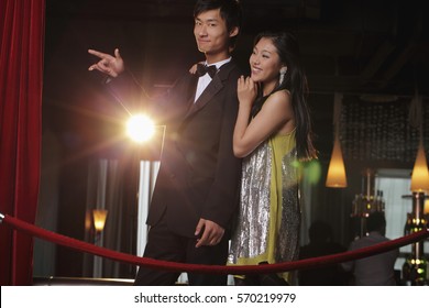 Young couple standing behind red rope at night