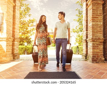 Young couple standing at hotel corridor upon arrival, looking for room, holding suitcases - Shutterstock ID 205324165